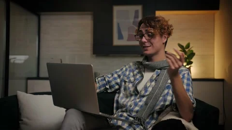 Young man make video call sitting at sofa in home interior.Happy guy doing Stockbeeldmateriaal 221618628