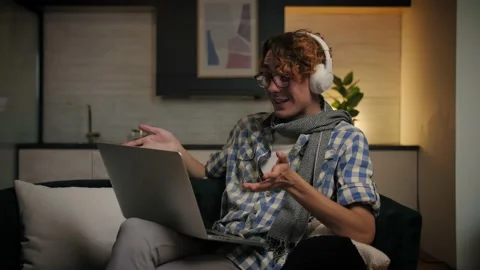 Young man make video call sitting at sofa in home interior.Happy guy with Stock Footage 221619614