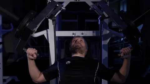 A young man makes a Bench press on a simulator.low key frame Stock Footage 115250421