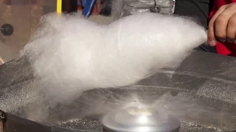 A young man makes cotton wool from sugar. Near the device for its manufacture .. Video stock 100601051