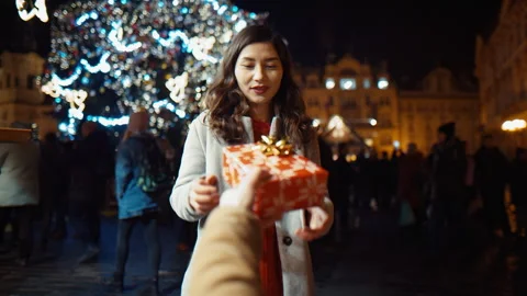 A young man makes a gift to an Asian girl in the new year and Christmas on the Stock Footage 166095243