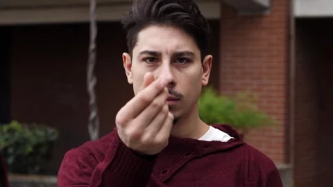 Young man makes hand gesture symbolizing money with a knowing smile Stock Footage 306680441