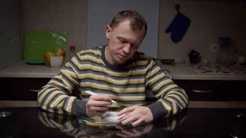 A young man makes notes in a notebook, sitting in the evening in the kitchen Stock Footage 134680411