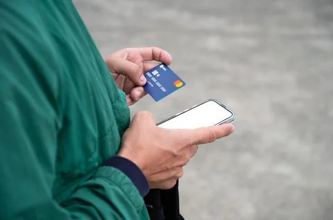 Young man makes a purchase through a smartphone, holding a credit card and a Stock Photos