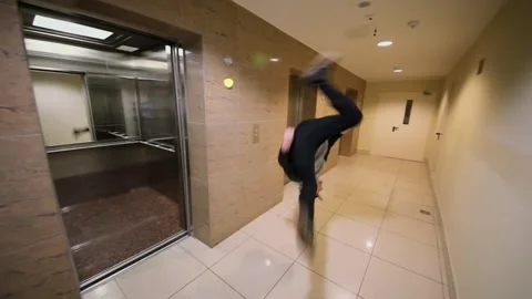 Young man makes salto and runs to cabin of elevator in house. Slow motion Stock Footage 276377619
