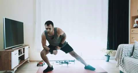 Young man makes warm-up movements before starting sports at home 動画素材 143931480
