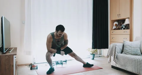 Young man makes warm-up movements before starting sports at home 動画素材 143932833