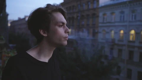 A young man with makeup, standing on the balcony, smoking a cigarette. Stockbeeldmateriaal 202307142