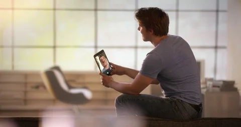 Young man making funnny grimaces with a tablet on his couch Stock Footage 78608132
