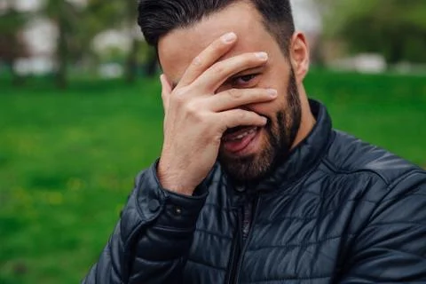 Young man making funny faces and covering his face with a hand. Stock Photos