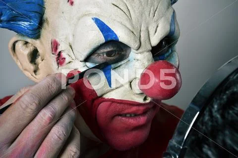 Young man making up himself as an evil clown Stock Photos