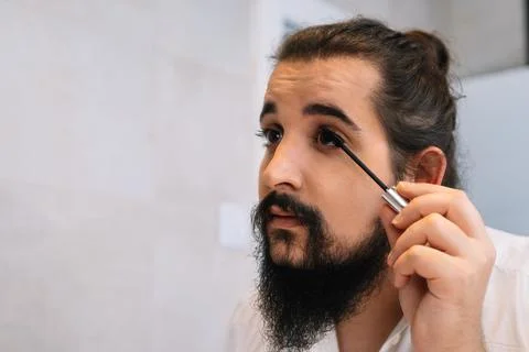 Young man making up his eyelashes in the bathroom. Using eyelash mask. Stock Photos