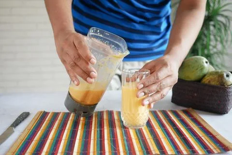 Young man making mango smoothie and a blender on table Stock Photos