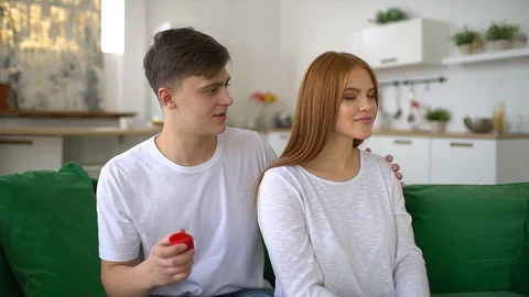 Young man making marriage proposal to surprised woman with ring in red gift box Stock Footage 86196014