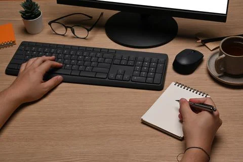 Young man making notes on notebook and working with computer. Stock Photos