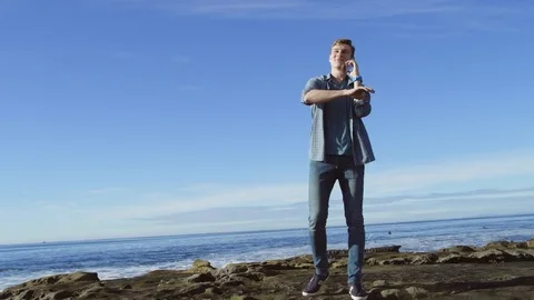 Young man is making a phone call on a beach Stock Footage 75753343