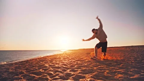Young man making somersaults in slow motion on the sandy beach Stock Footage 185773597