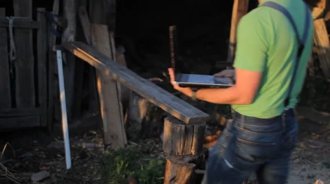 Young man making video call at the sawmill with laptop computer in his hands Video stock 64776243