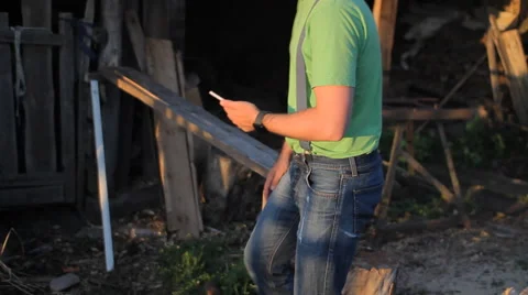 Young man making video call at sunset. A man sits at the sawmill Stock Footage 64776597