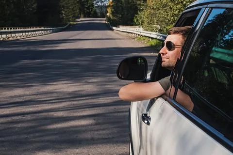 Young man man looking out of the driver window of his car, Stock Photos