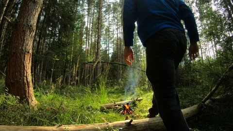 A young man. The man sits down on the log next to the fire. Stock Footage 93860867
