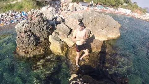 A young man man standing on land on rocks, floating starfish floating in a wild Stock Footage 80167397
