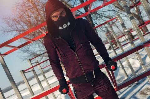 Young man in mask exercising on bars outdoors Stock Photos