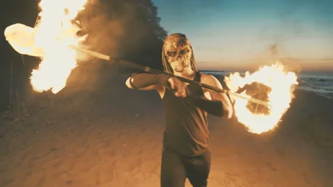 Young man in a mask of a predator shows a fire show on the beach. Video stock 91710155