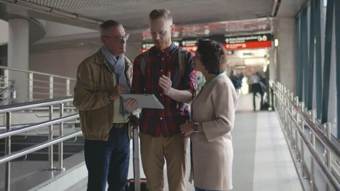 Young man with mature parents using tablet computer at airport while waiting for Video stock 123314465