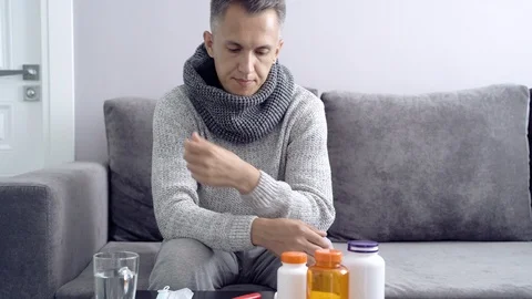 Young man measures the temperature sitting on sofa in home. Stock Footage 112645927