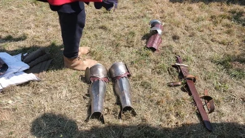 Young man in Medieval clothes build knight armor on grass Stock Footage 113186909