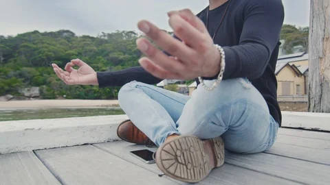 Young Man Meditates Alone Sitting on Wharf. Mid Shot Cranes Up Stock Footage 129246143