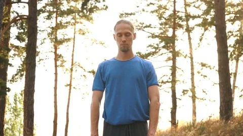 A young man meditates in the woods by the river Stock Footage 80793825