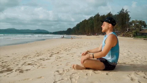 Young man meditating on the beach 動画素材 93351793