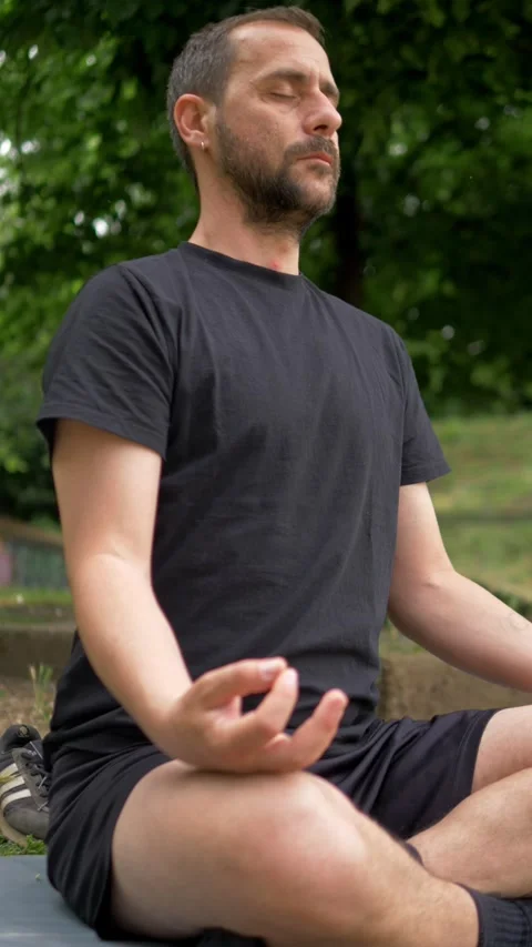 Young Man Meditating in Cross-Legged Yoga Pose During Outdoor Park Session Video stock 335696656