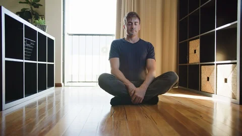Young man meditating on floor while at home. Lock down, isolation, coronavirus,  Stock Footage 130110870