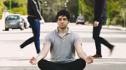 Young man meditating in the middle of the street, for mindfulness concepts Stock Footage