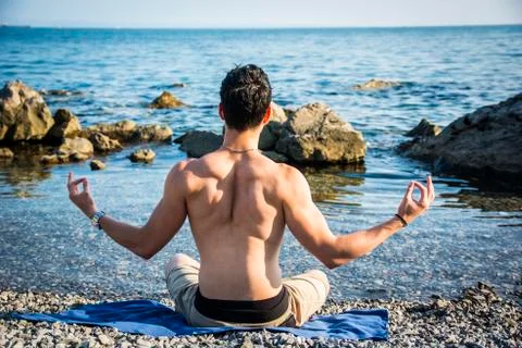 Young Man Meditating or Doing Yoga Exercise by Sea Foto stock