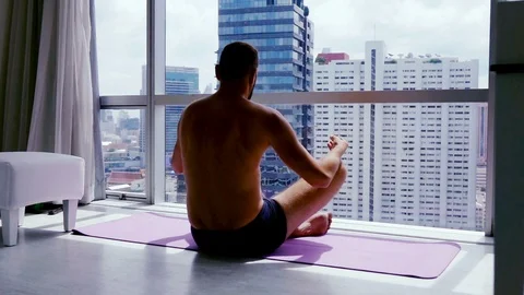 Young man meditating  by the window at home, super slow motion Stock Footage 84394587