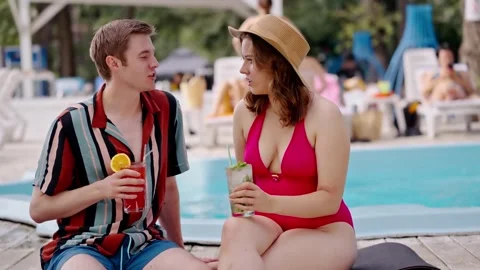 Young man meet hot chic girl in red bikini drinks alcohol at poolside. Couple Stock Footage 257209270