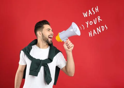 Young man with megaphone on red background. Wash your hands to avoid coronavi Stock Photos