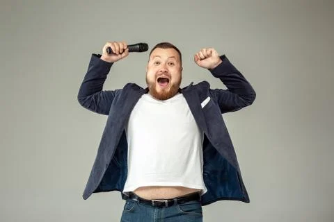 Young man with microphone on gray background, leading with microphone Stock Photos