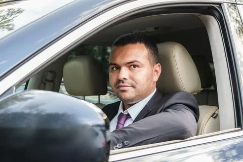 Young man of Middle Eastern appearance in a business suit is driving an expen Stock Photos