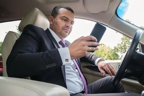 Young man of Middle Eastern appearance in a business suit is driving an expen Stockfoto's