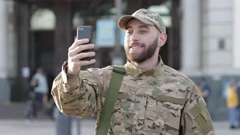 A young man in a military uniform is standing at the station, talking via vid Stock Footage