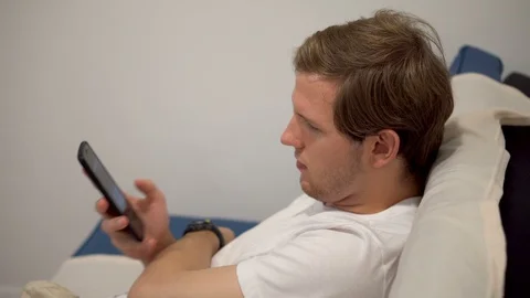 Young Man Mindlessly Scrolling Social Media on Smartphone Stock Footage 124452447