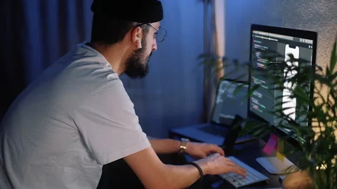 Young man mobile developer writes program code on a computer Stock Footage 166691005