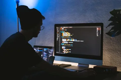Young man mobile developer writes program code on a computer. 스톡 사진
