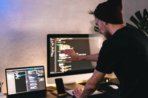 Young man mobile developer writes program code on a computer. 스톡 사진