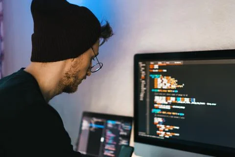 Young man mobile developer writes program code on a computer. 写真素材